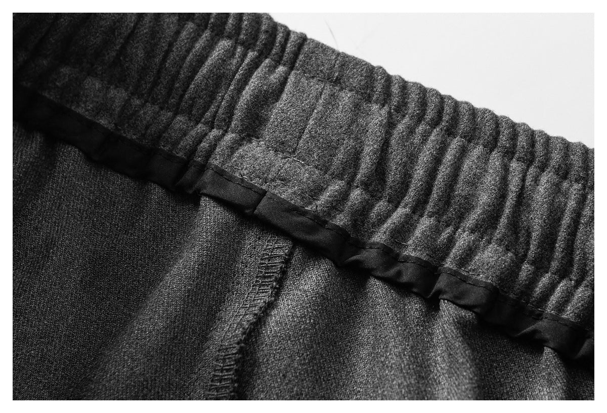 Close-up of a charcoal garment's gathered waistband interior, black trim, and seam stitching.