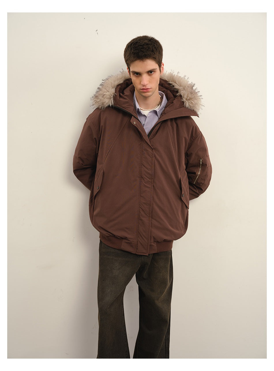 Model wearing a dark brown padded jacket with a beige fur-trimmed hood and dark trousers, facing forward.