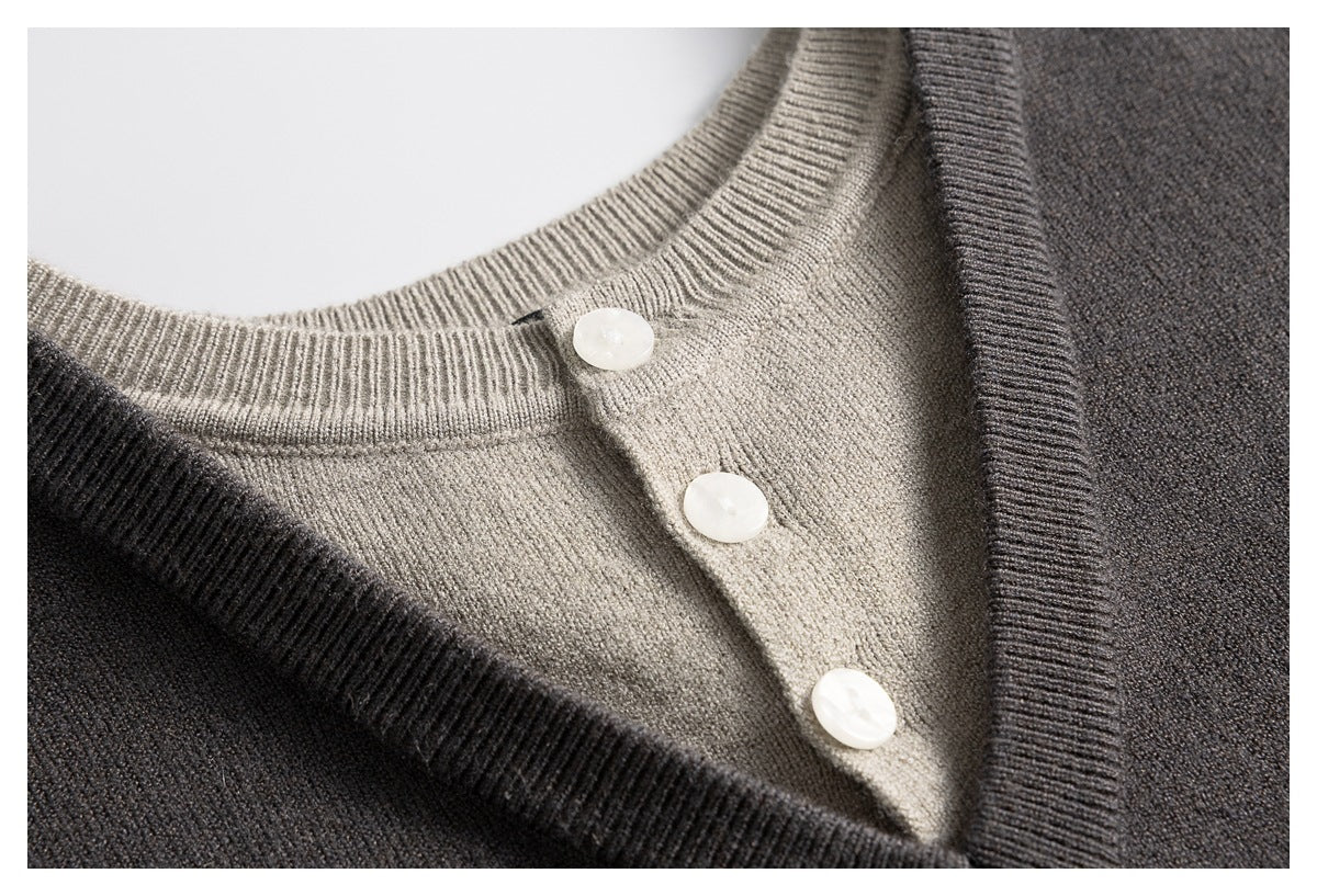 Close-up of a taupe ribbed neckline and three white buttons beneath the charcoal sweater's V-neck trim.