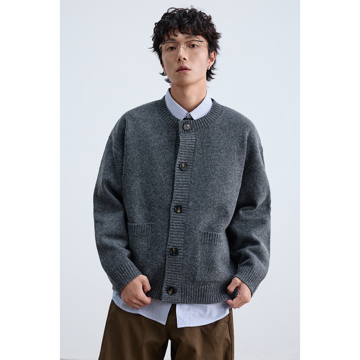 Front view of a model wearing a charcoal gray button-front cardigan with ribbed trim and two patch pockets.