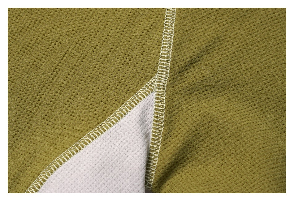 Close-up of olive-green textured fabric with a white insert and visible overlocked seams.