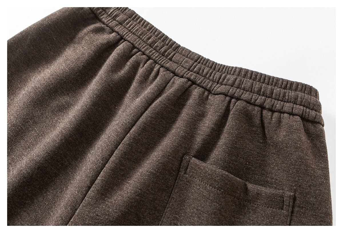 Close-up of brown trousers showing the elastic back waistband and a rectangular rear pocket.