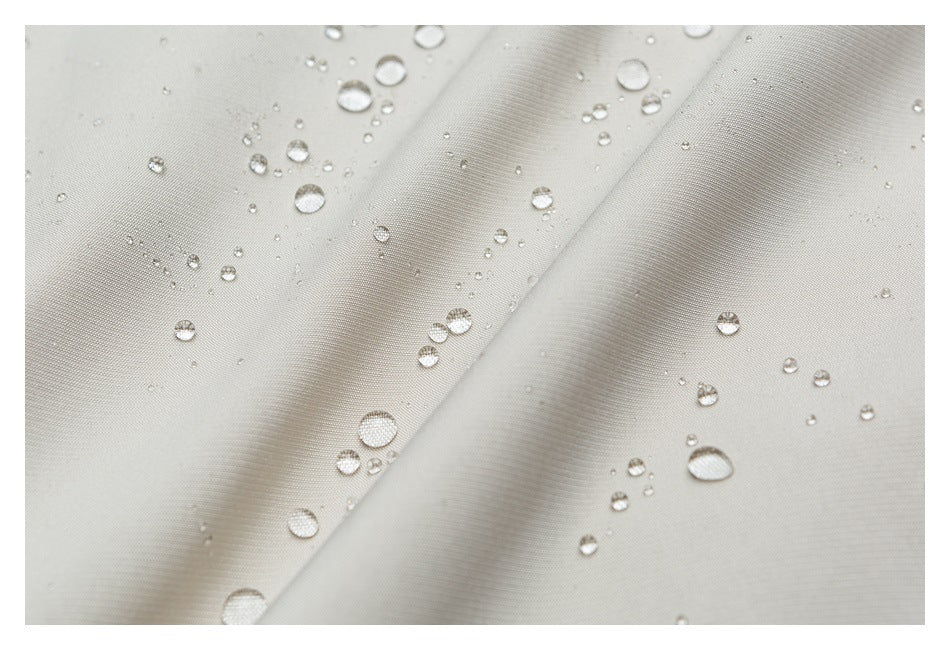 Water droplets bead on the surface of folded light beige garment fabric.