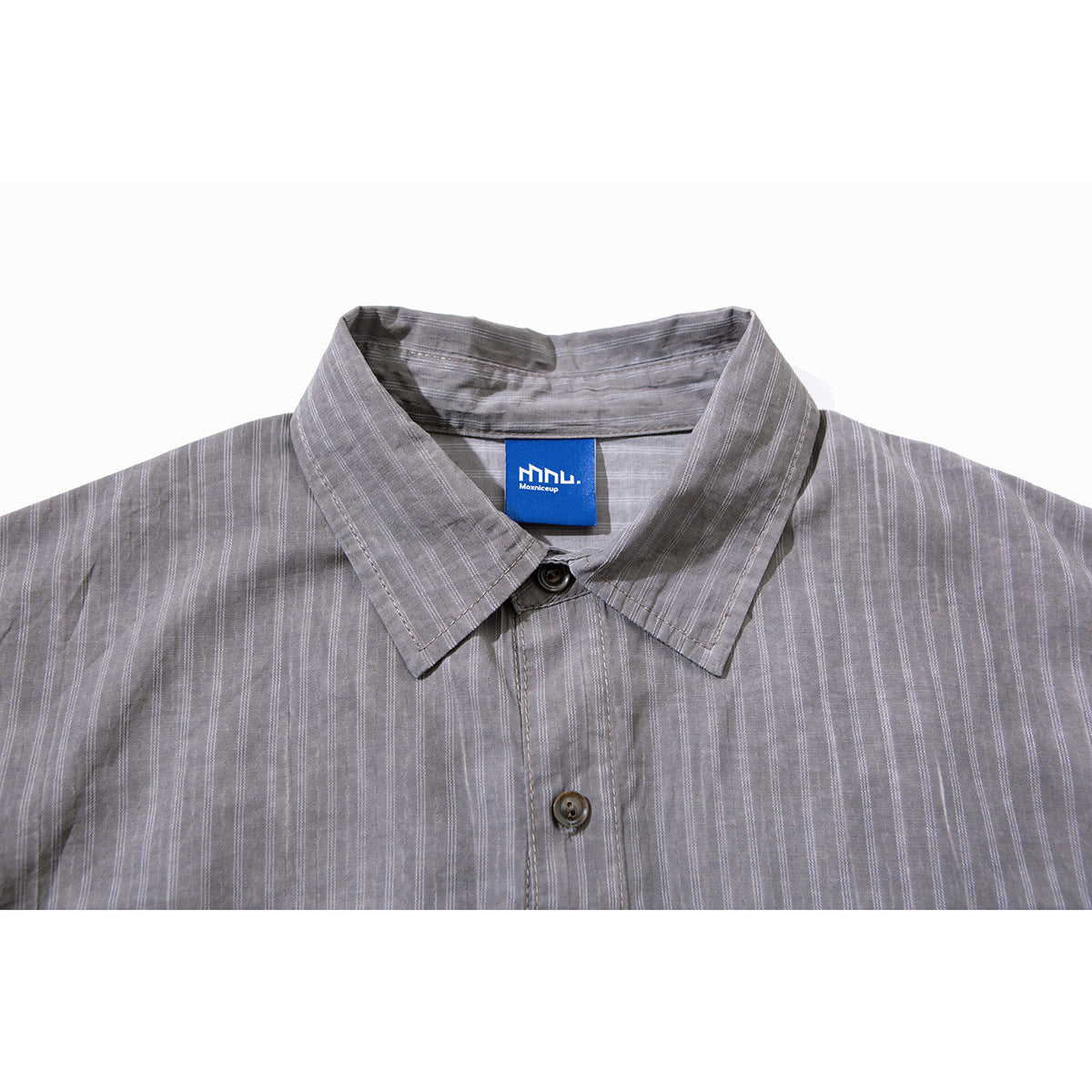 Close-up of a gray striped shirt collar, top button, and blue neck label.