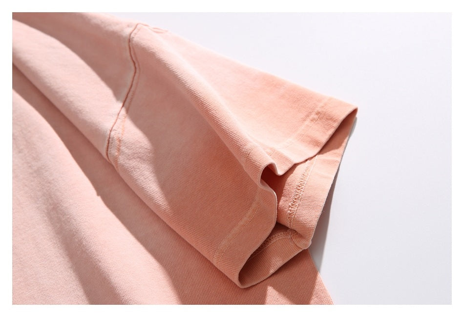 Close-up of the peach T-shirt sleeve, showing the cuff and seam stitching.