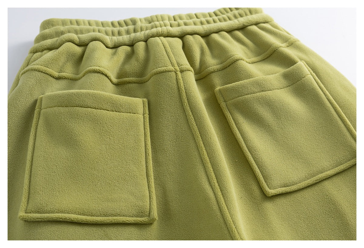 Back view of olive-green fleece pants laid flat, showing an elastic waistband and two large patch pockets.
