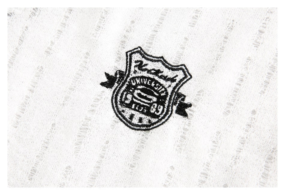Close-up of a black embroidered crest on white fabric with a raised vertical texture.