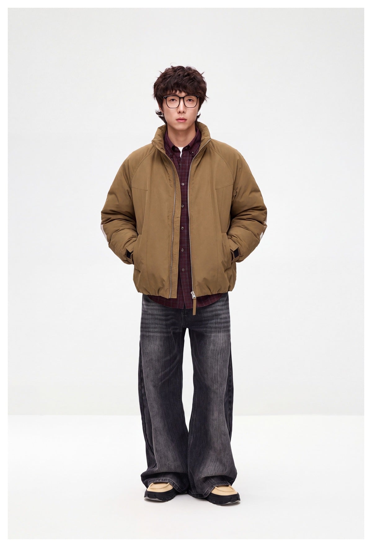 Front view of a model wearing a brown zip-front jacket with a stand collar over a burgundy plaid shirt.