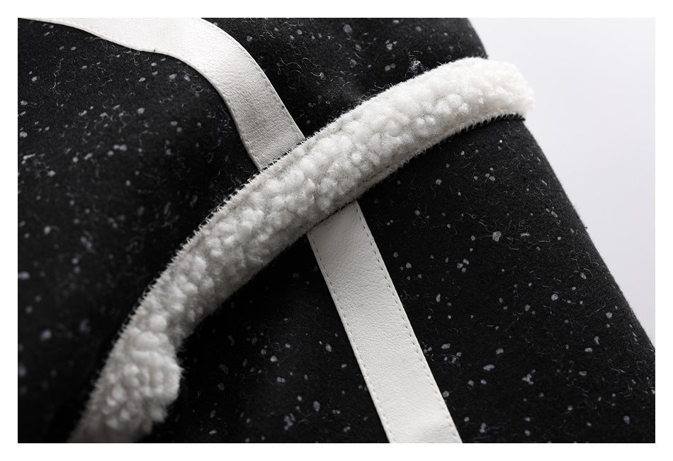 Close-up of black speckled fabric with a white trim strip crossing beneath a curved white fuzzy edge.
