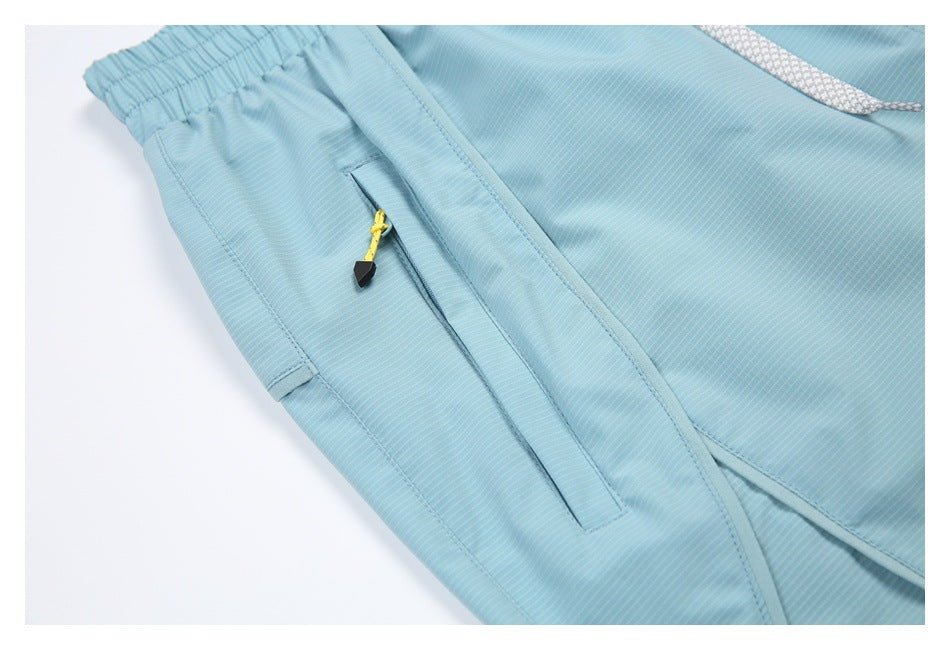 Close-up of a zip pocket on light blue striped bottoms, with a yellow cord zipper pull.