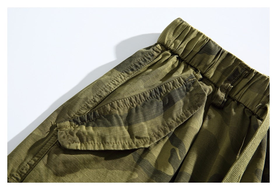 Close-up of a flap pocket and elastic waistband on the olive camouflage shorts.