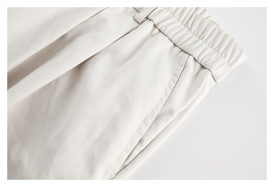 Close-up of off-white trousers showing a side pocket opening and gathered waistband.