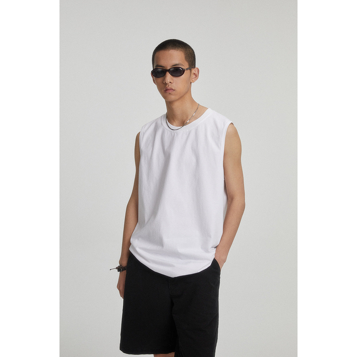 Model wearing a plain white sleeveless crew-neck top with black shorts.