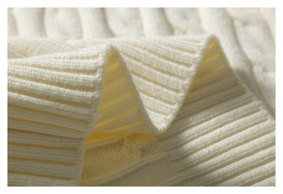 Macro view of the ivory sweater's ribbed knit edge and folded fabric.