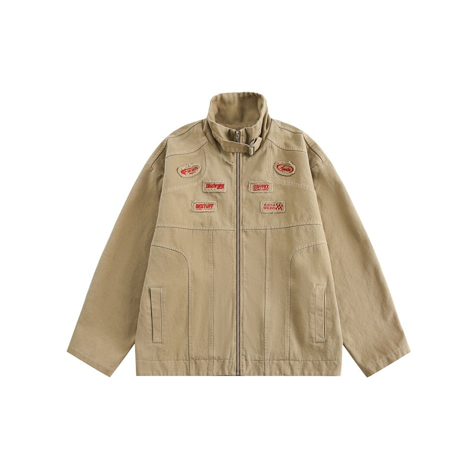 Khaki zip-front jacket with stand collar, buckle strap, red embroidered patches and front slash pockets, flat lay