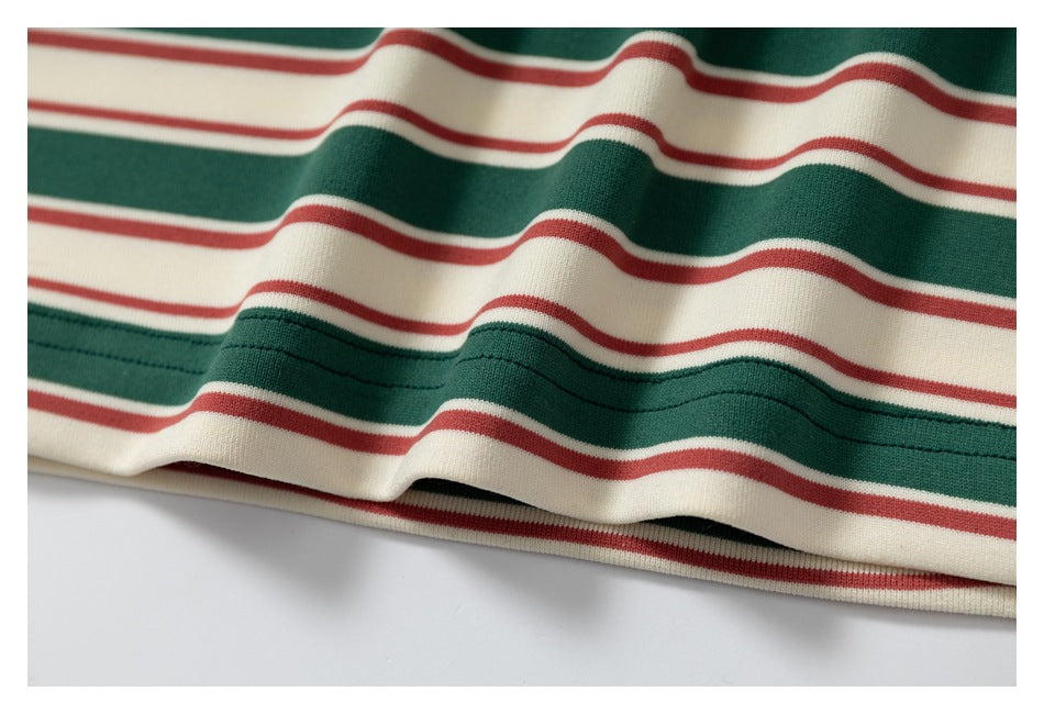 Close-up of the striped garment's hem, showing cream, dark green, and red bands and stitching.