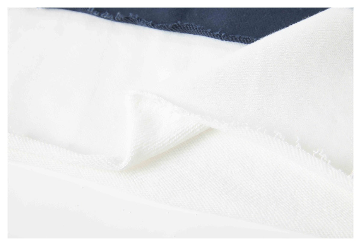 Close-up of overlapping white garment fabric and stitched edges against a navy panel.