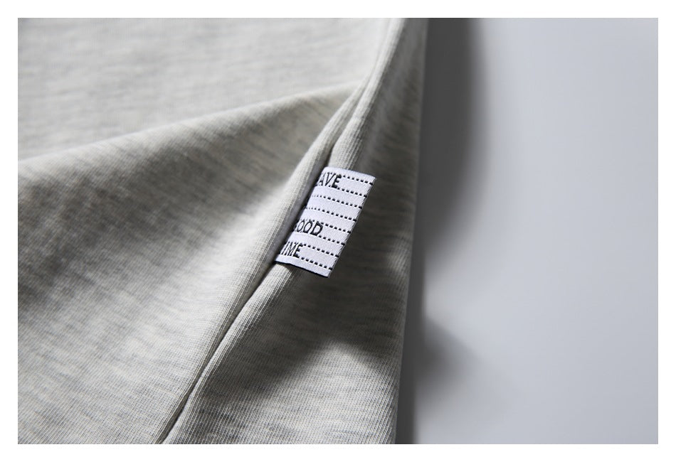 Close-up of a light gray T-shirt side seam with a small sewn fabric label.