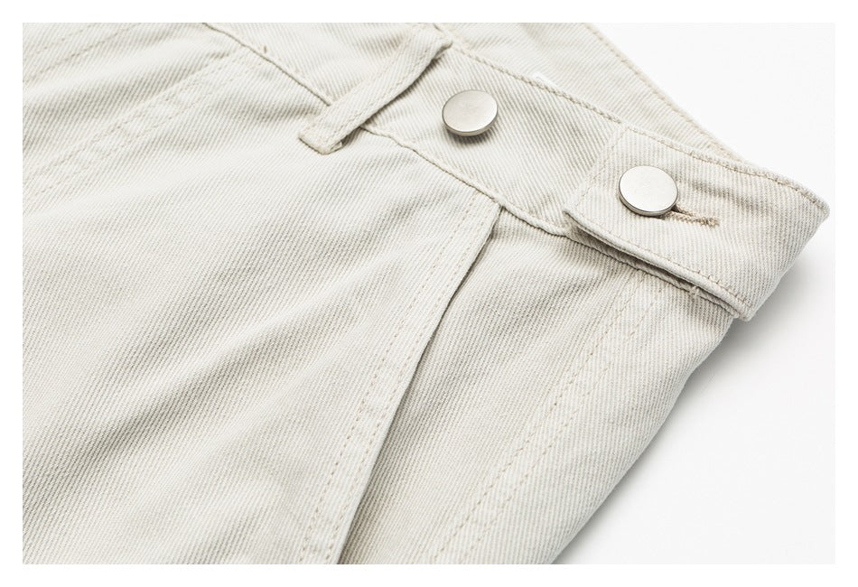 Close-up of off-white trousers showing the waistband, belt loop, and two metal buttons.