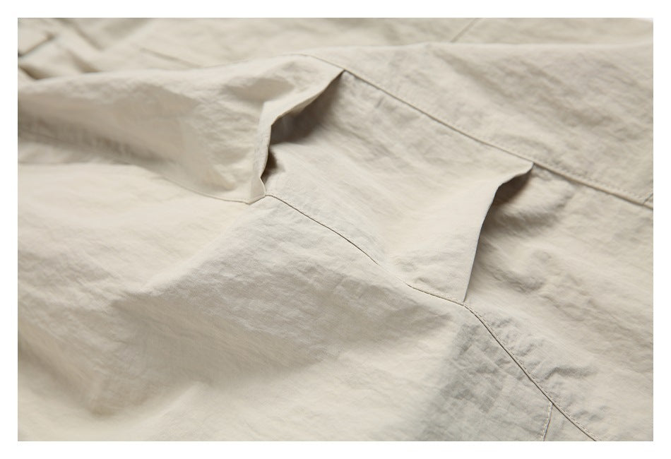 Close-up of light beige garment construction showing overlapping panels and stitched seams.