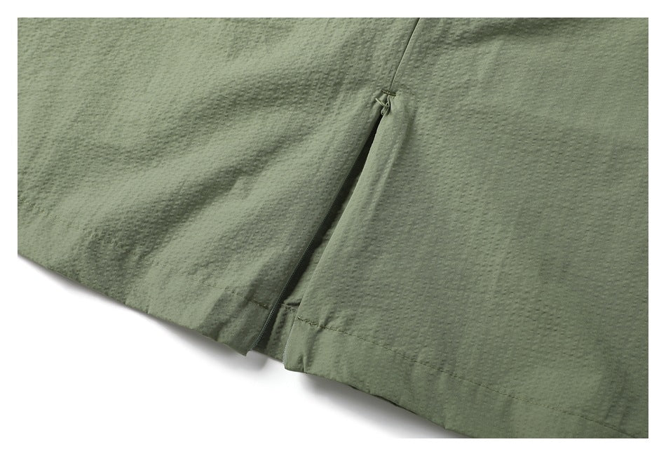 Close-up of a slit and stitched hem on gray-green fabric.