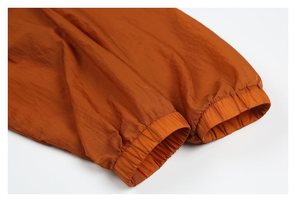 Close-up of rust-orange garment with gathered, elasticized hems and visible stitching.
