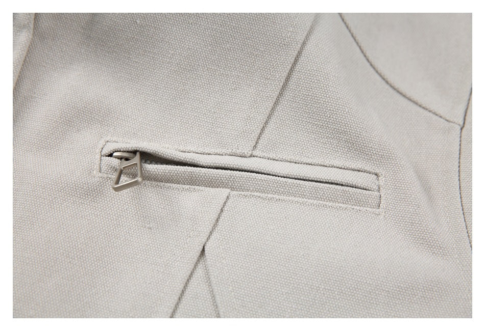Close-up of a beige jacket with a horizontal zippered pocket and metal pull.