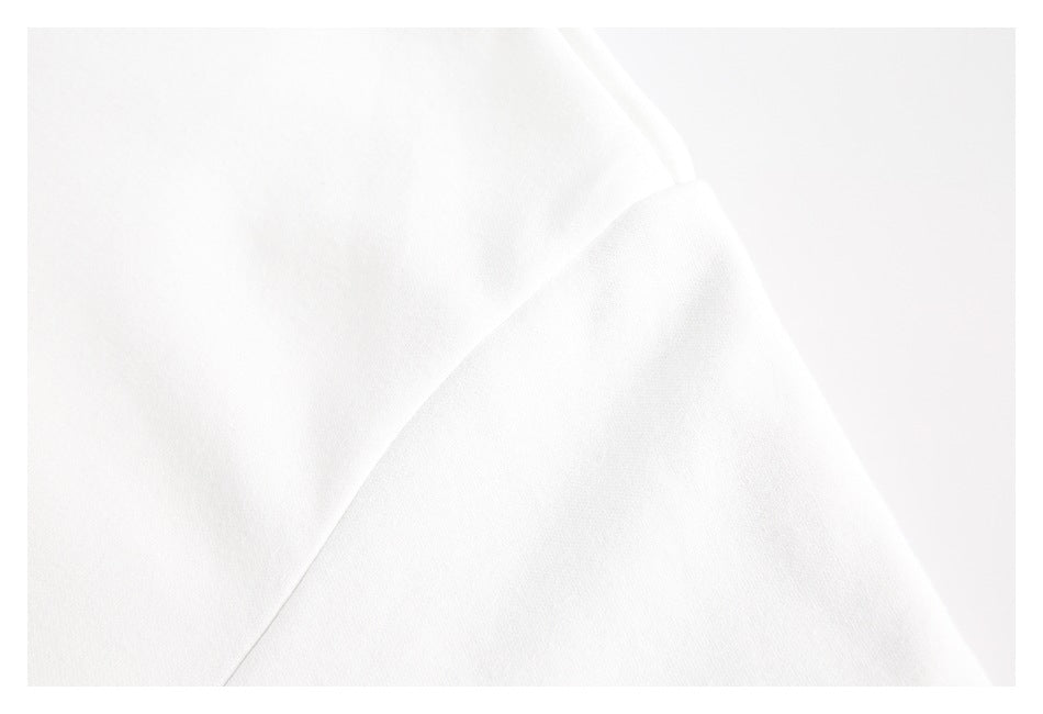 Close-up of white garment fabric folded along a curved stitched edge.