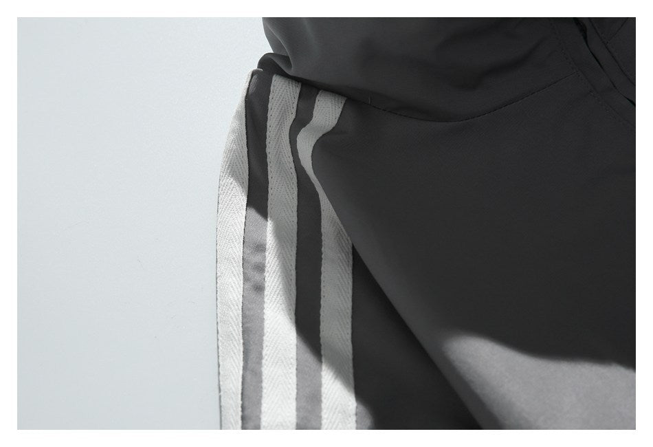 Close-up of charcoal pants with a light contrasting side stripe and visible seam.
