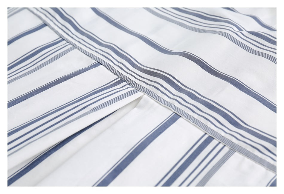 Close-up of white fabric with alternating navy and gray stripes, folded in overlapping layers.