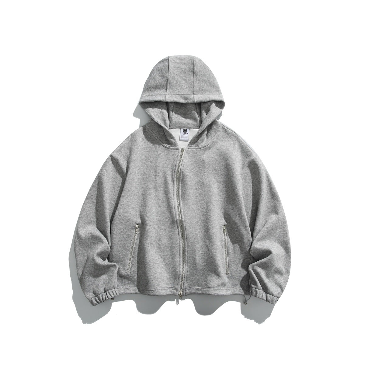 Heathered gray zip-front hoodie flat lay with paneled hood, curved zipper, zippered pockets and elastic cuffs