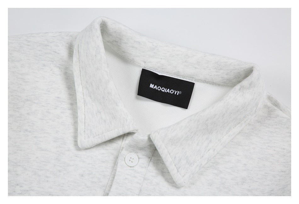 Close-up of the light gray heather shirt’s pointed collar, top button, and black neck label.
