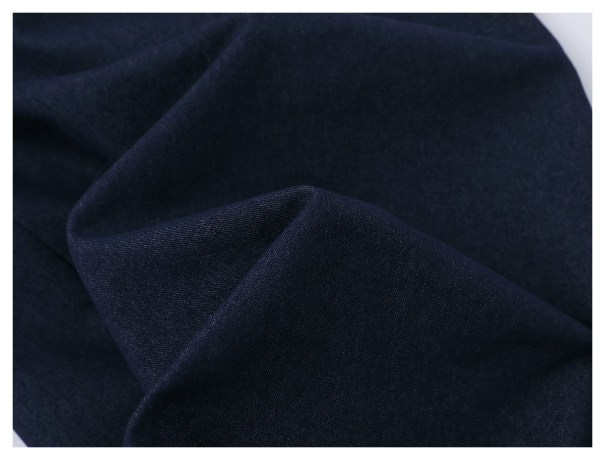Close-up of dark navy fabric folded to show its fine woven texture.