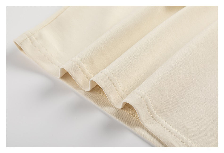 Close-up of the stitched hem on cream garment fabric.