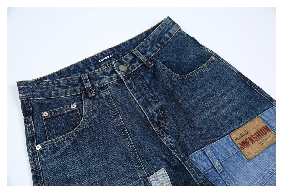 Angled close-up of the jeans' front waistband, button, pockets, and contrasting light blue denim patchwork.