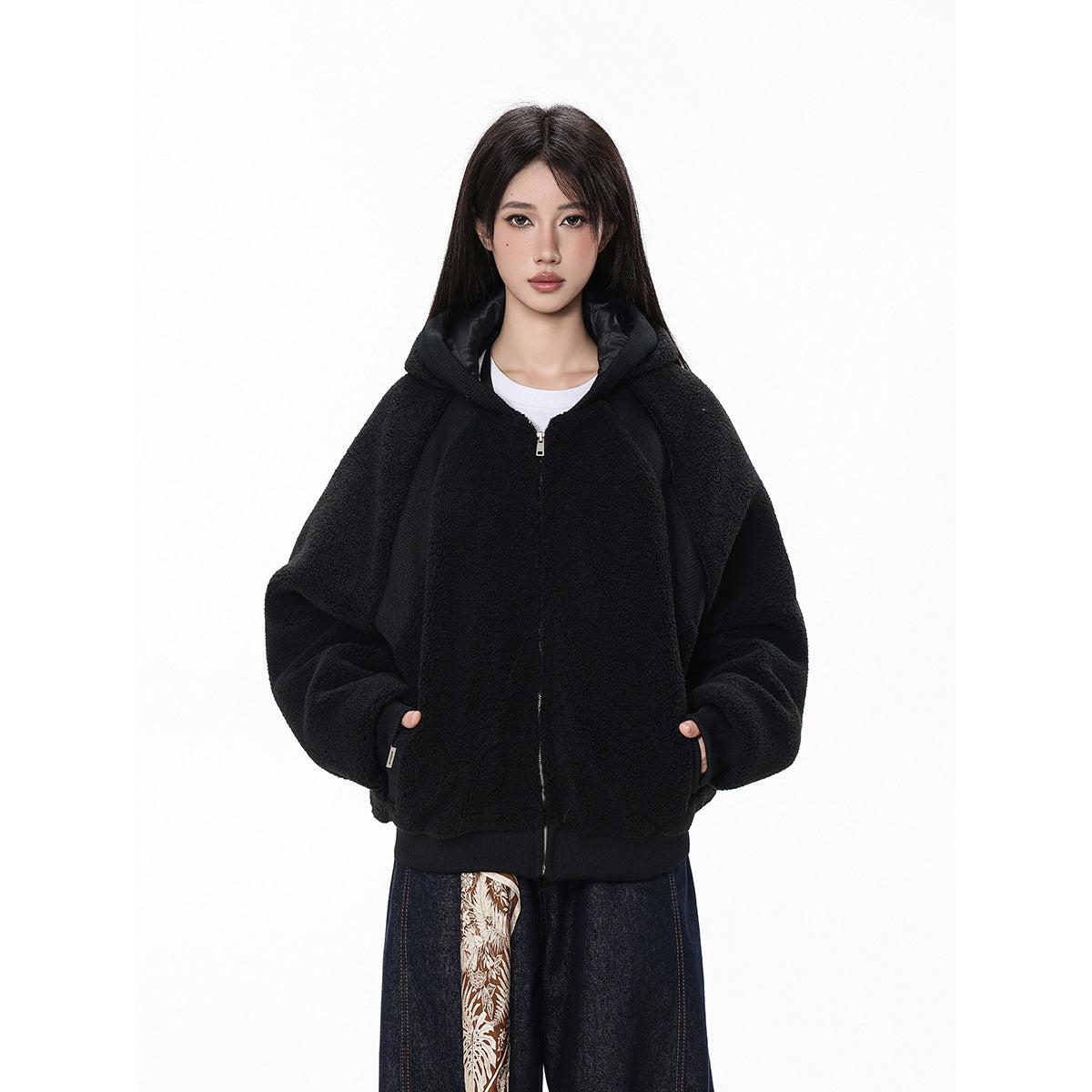 Front view of a model in a black hooded zip-up jacket with roomy sleeves and ribbed trim.