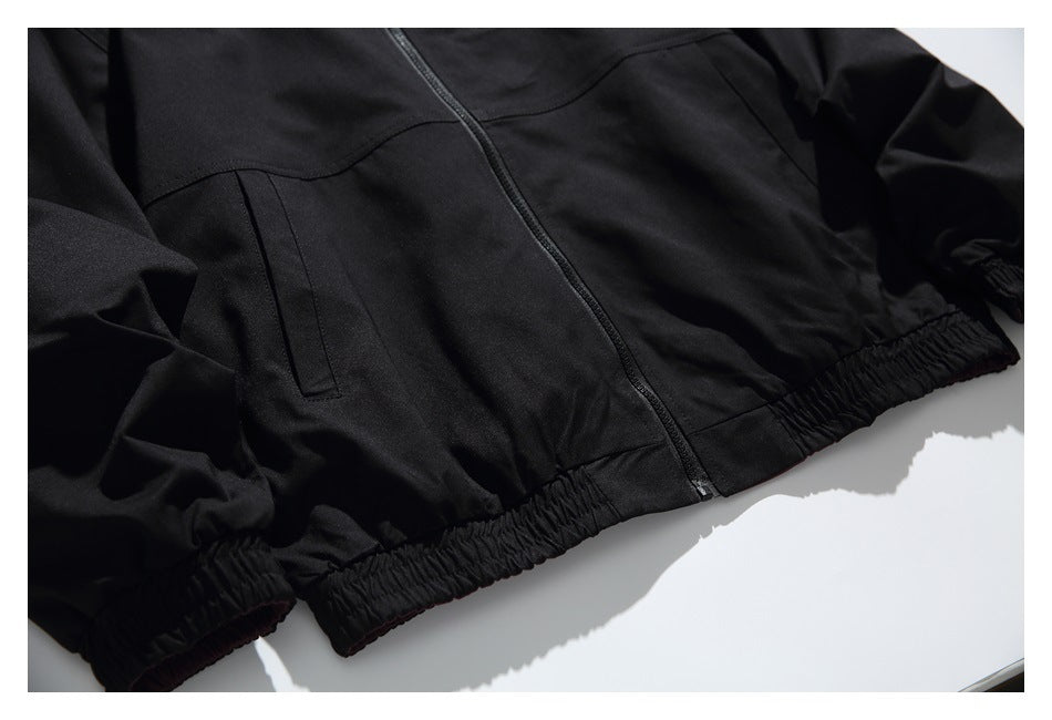 Close-up of the black jacket front, showing its zipper, pocket, and gathered elastic hem.