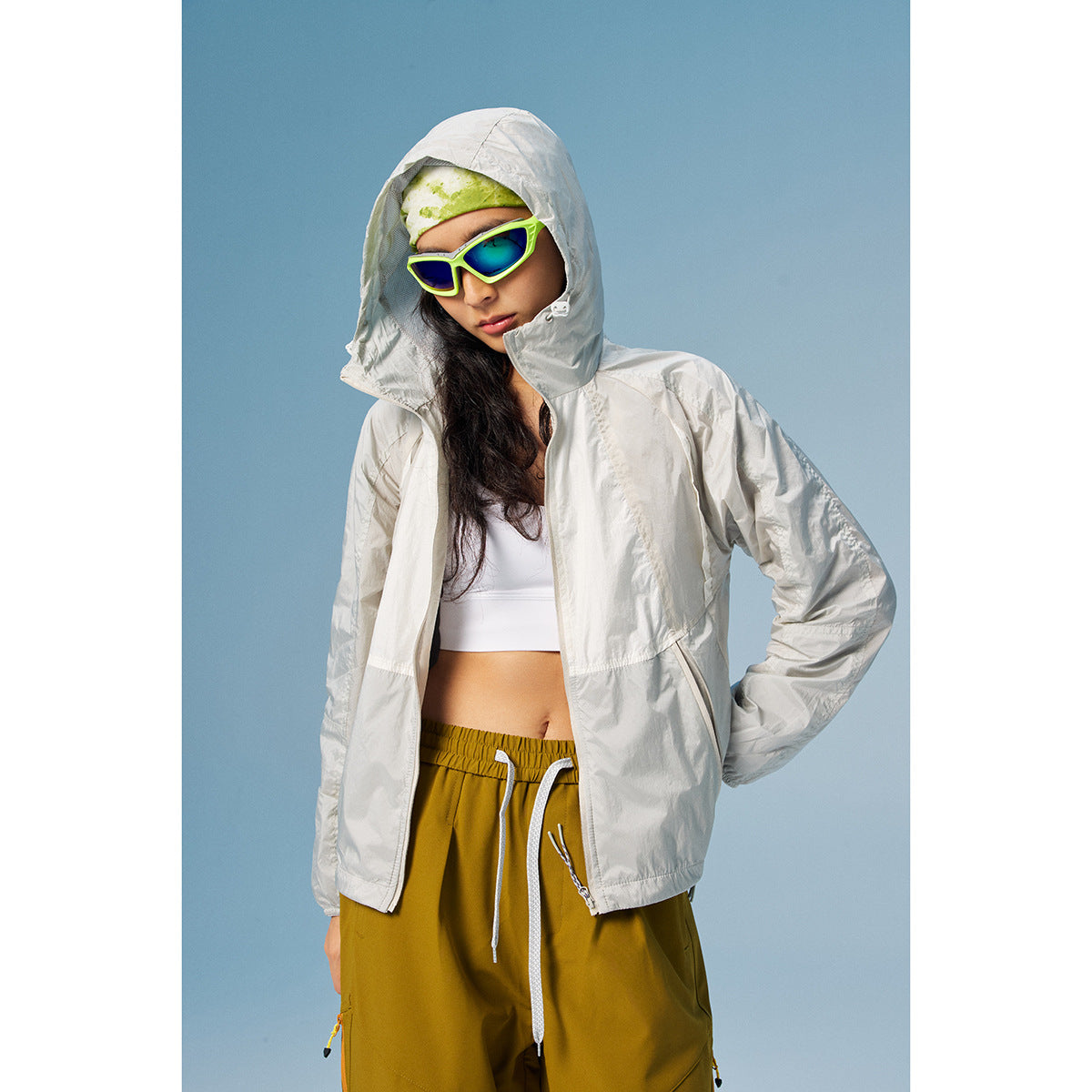 Model wearing a light gray hooded jacket over a white top with mustard yellow pants.