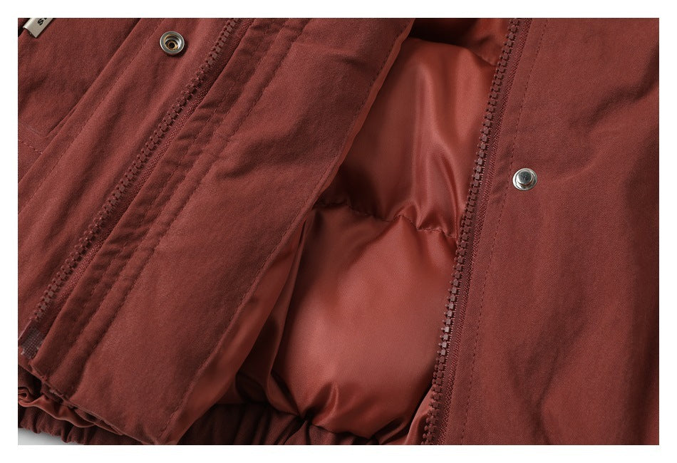 Close-up showing the rust-red garment's open front zipper and smooth inner lining.