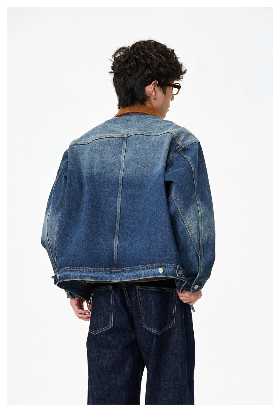 Rear view of a model wearing a dark blue denim jacket with a contrasting shoulder yoke and brown collar.