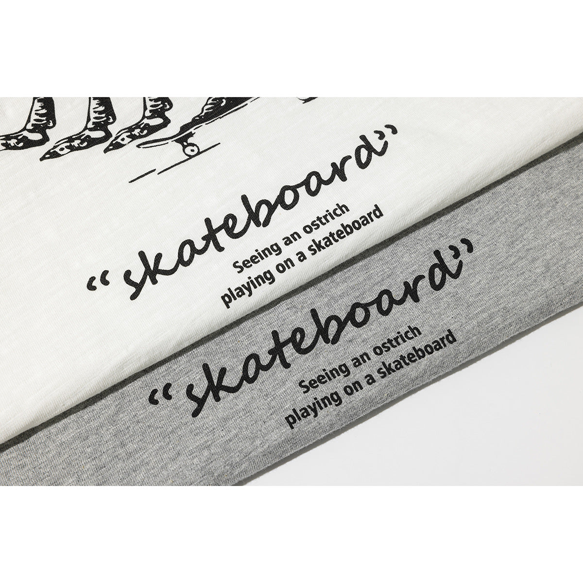 Close-up of white and heather-gray T-shirts showing the same black ostrich skateboard graphic and English text.