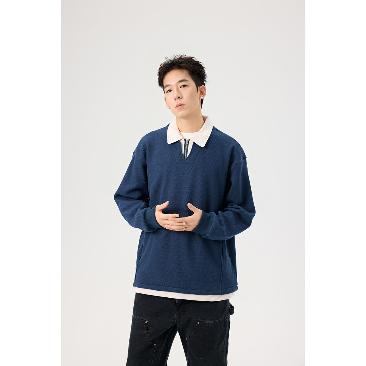 Closer view of a model wearing a navy pullover with a white collar and short zip placket.