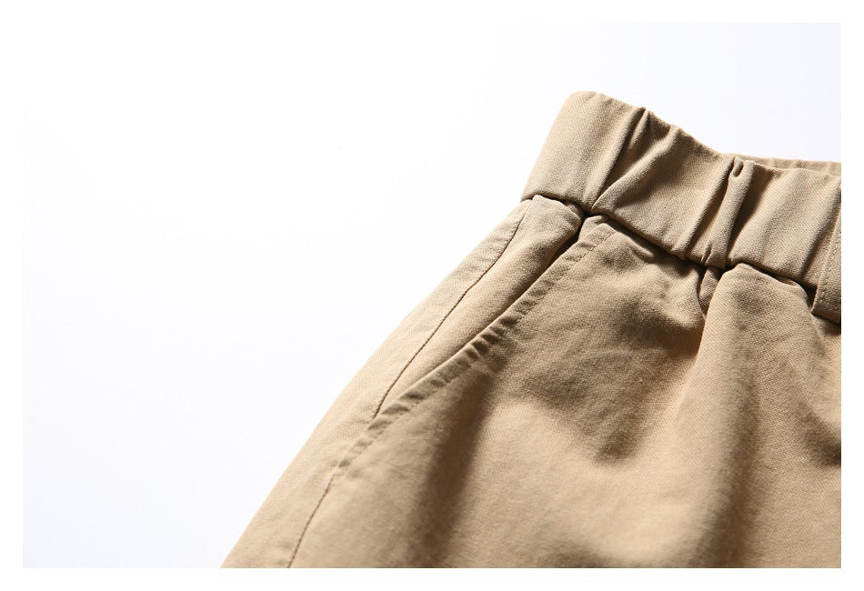 Close-up of the tan shorts' elastic waistband and slanted side pocket opening.