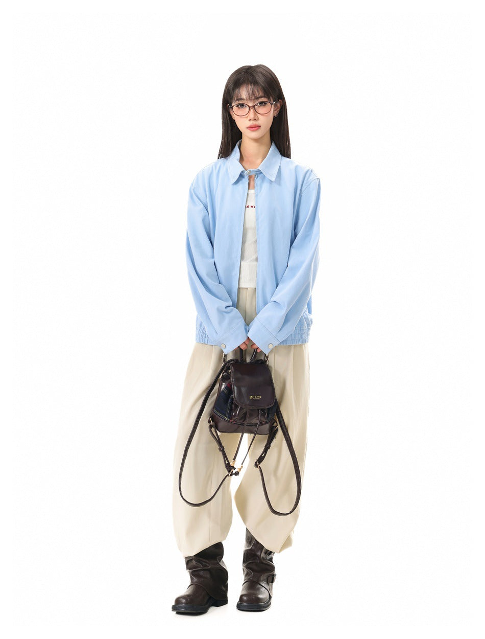Full-length view of model in light blue zip jacket, white top, cream trousers and dark brown boots