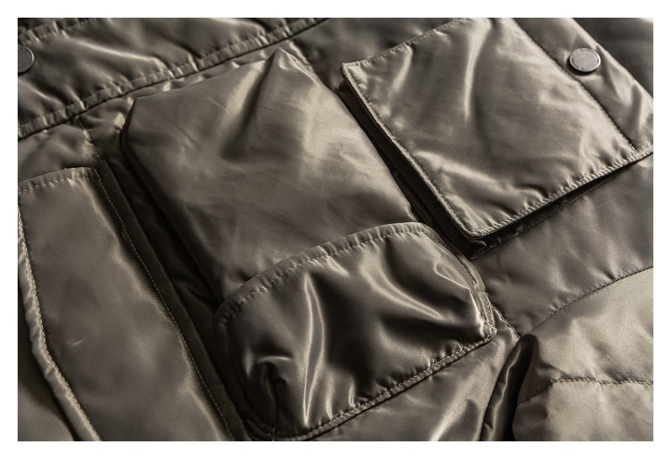 Close-up of a taupe jacket's sleeve and overlapping flap pockets with snap buttons.