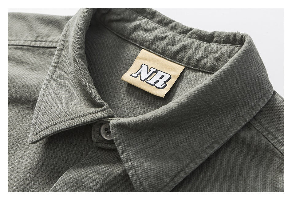 Close-up of a charcoal gray shirt collar, button, and beige neck label with an NR logo.