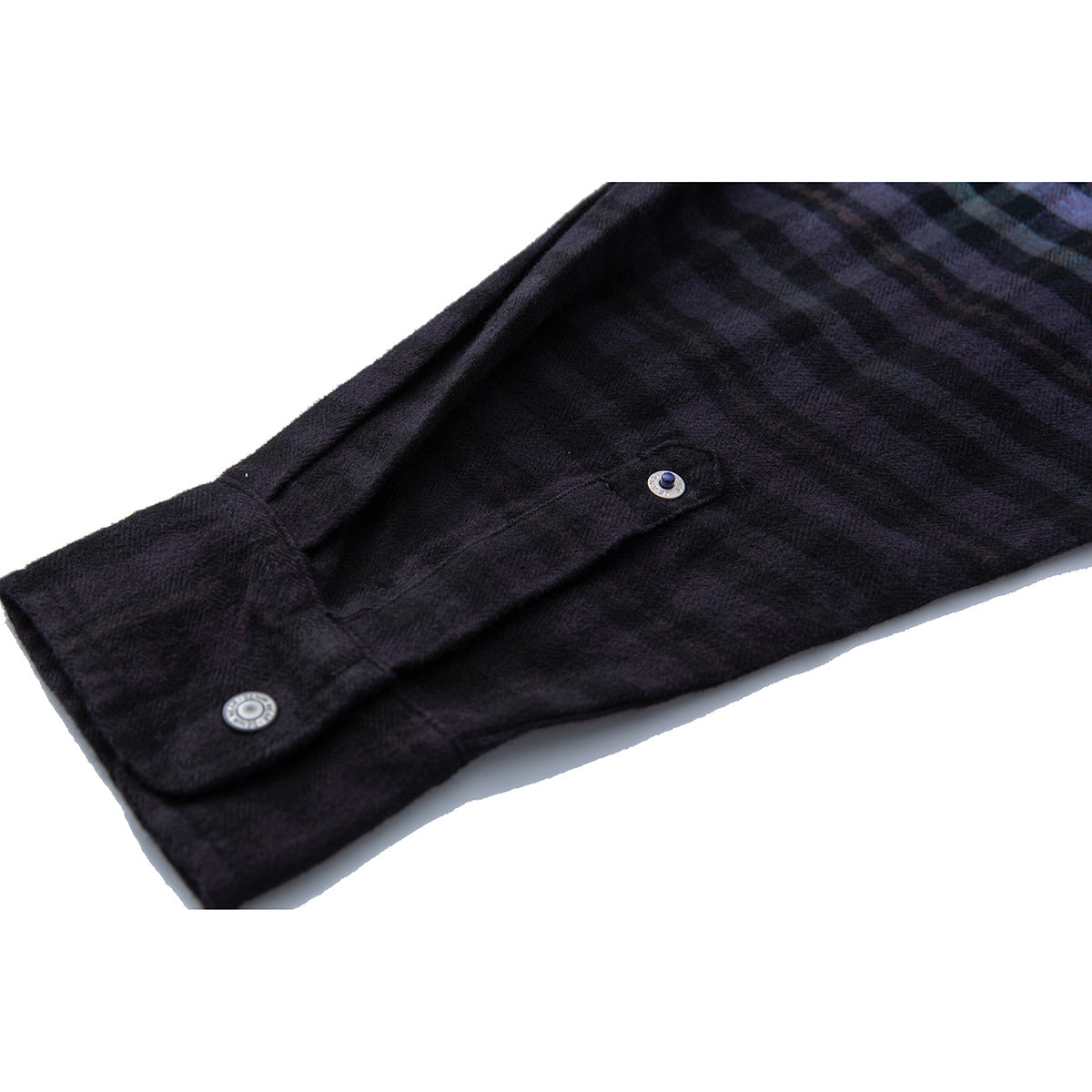 Close-up of a dark plaid shirt cuff with two silver-tone buttons.