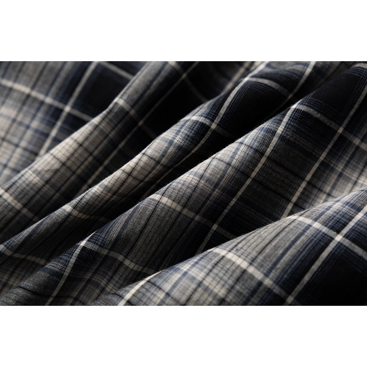 Macro view of the black, gray, and cream plaid pattern on a shirt, shown in soft folds.
