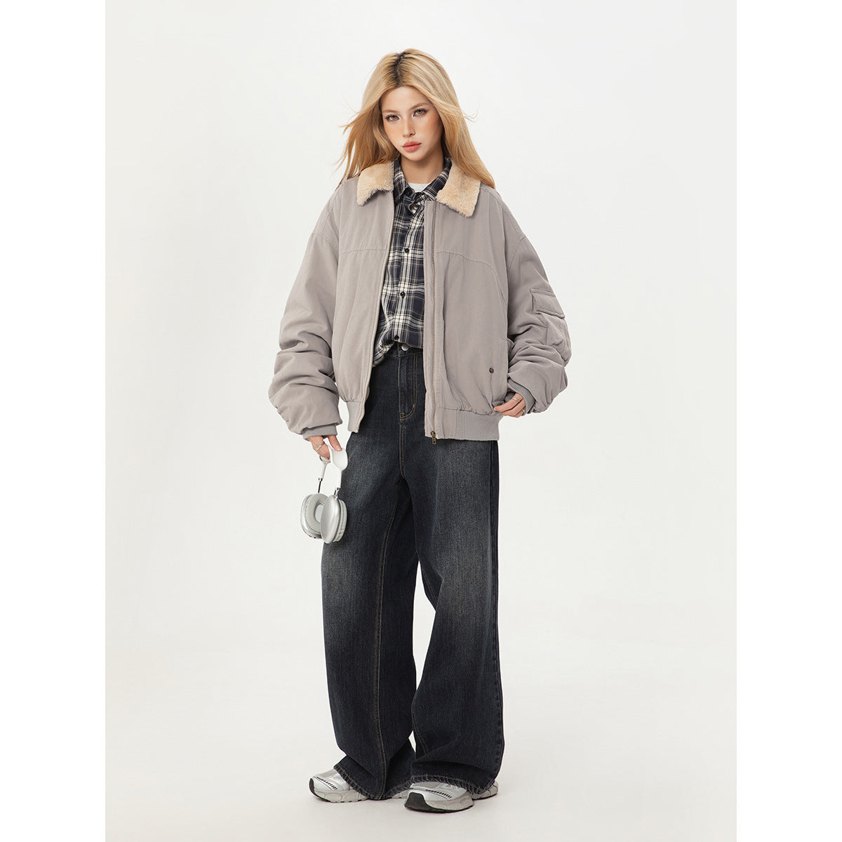 Front view of a model wearing a light gray bomber jacket with a cream shearling collar and dark jeans.