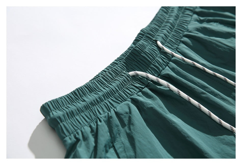 Close-up of teal shorts showing the gathered elastic waistband and patterned white drawstrings.